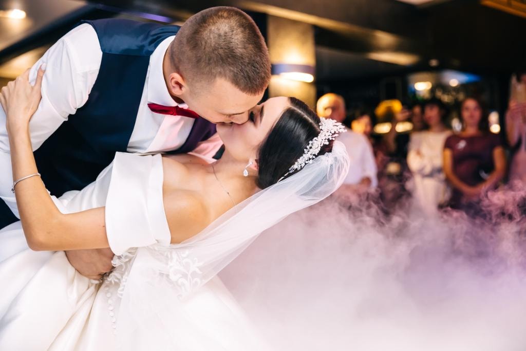 Couple laughing and enjoying a wedding dance lesson in a bright studio